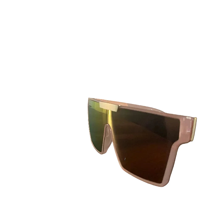 A pair of oversized shield-style sunglasses with a translucent pink frame and mirrored lenses, resting on a dark wooden table in an indoor setting.