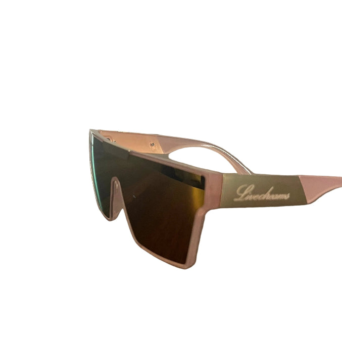 A pair of shield-style sunglasses with a metallic rose gold frame and dark mirrored lenses, resting on a dark wooden table. The brand name 'Breechcases' is printed on the temple arm.